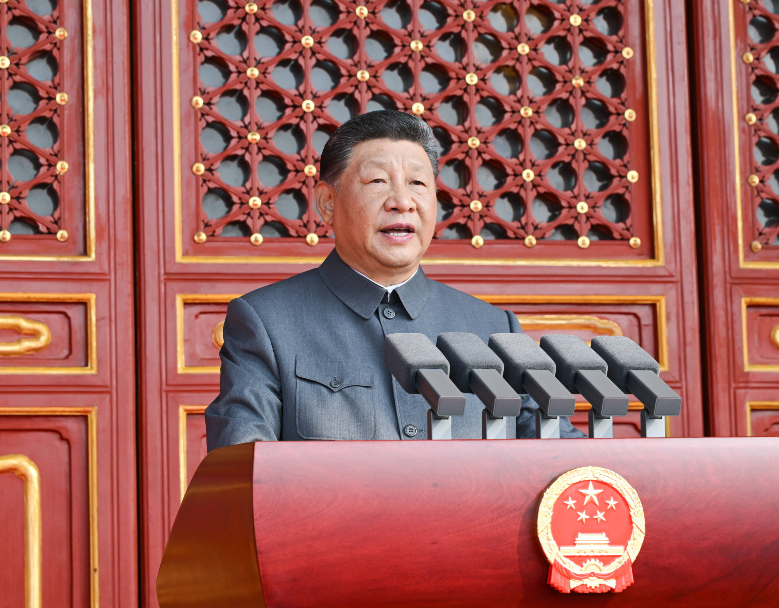 Col Mao gris, cinq micros, laque rouge et emblème national : le portrait officiel diffusé par Chine nouvelle reprend l'iconographie maoïste jusqu'au cadrage en légère contre-plongée qui grandit l'orateur. Photo officielle