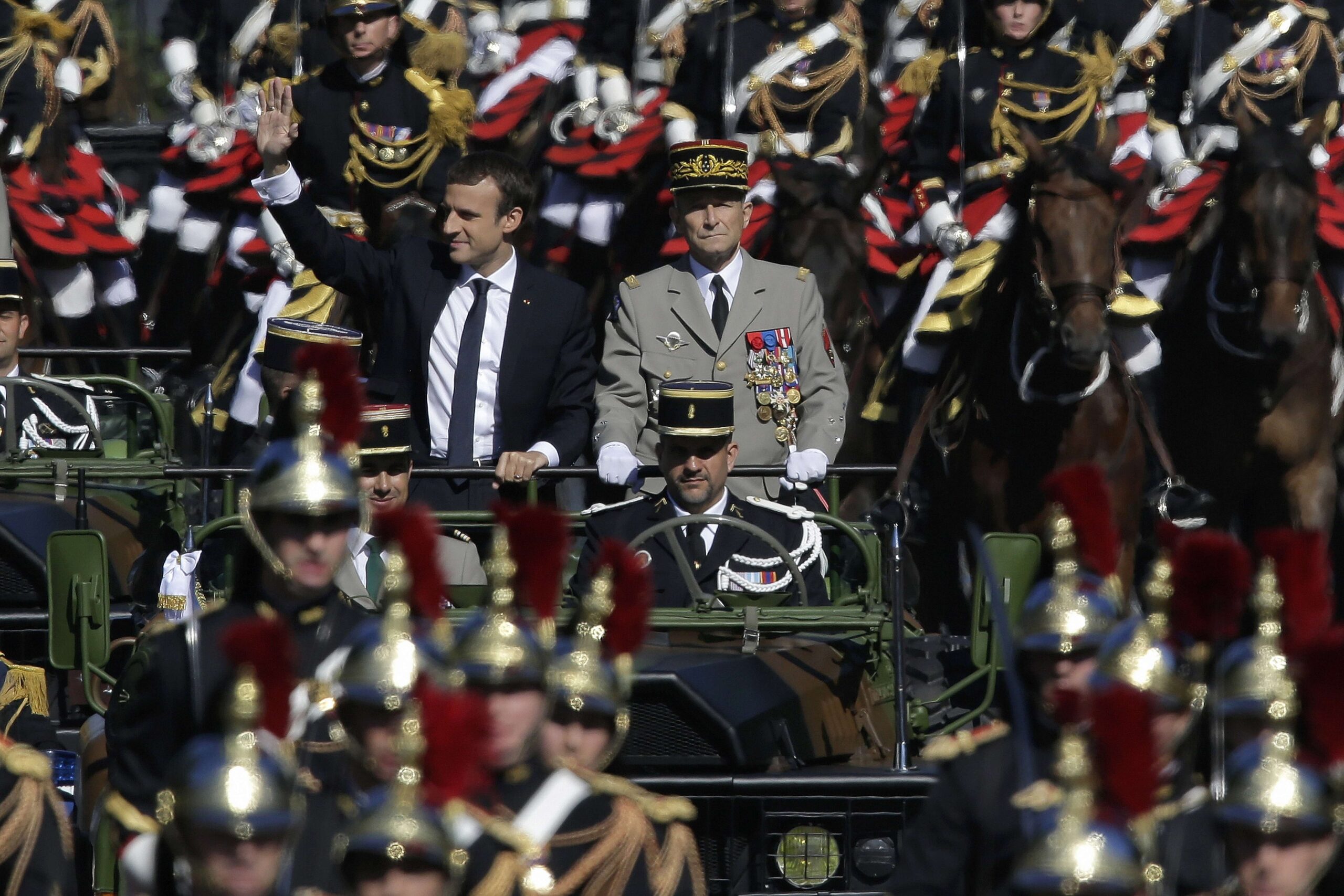 14 juillet 2017 : le premier défilé d’Emmanuel Macron. Le président alors âgé de 40 ans salue depuis le command-car, aux côtés du général de Villiers qui démissionnera cinq jours plus tard sur fond (entre autres) de coupes budgétaires. Photo : Markus Schreiber / AP