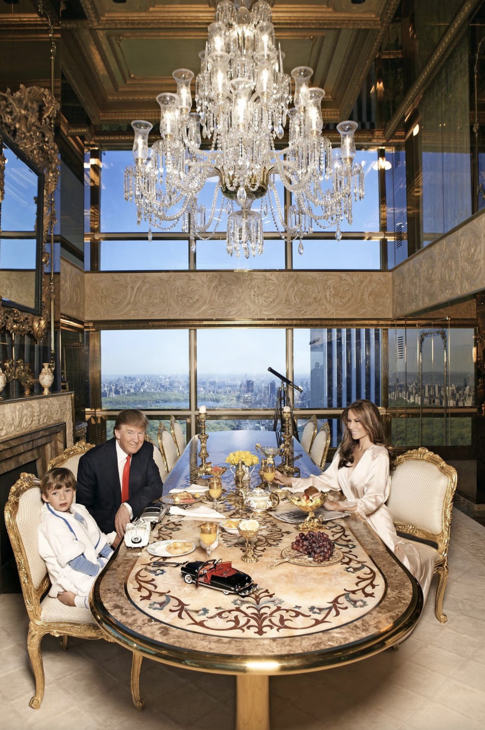 Donald Trump, Melania and Barron at breakfast in the dining room of the triple-height suite: marble-topped table, gilded seating, crystal chandelier, bay windows overlooking Central Park. Regine Mahaux/MT