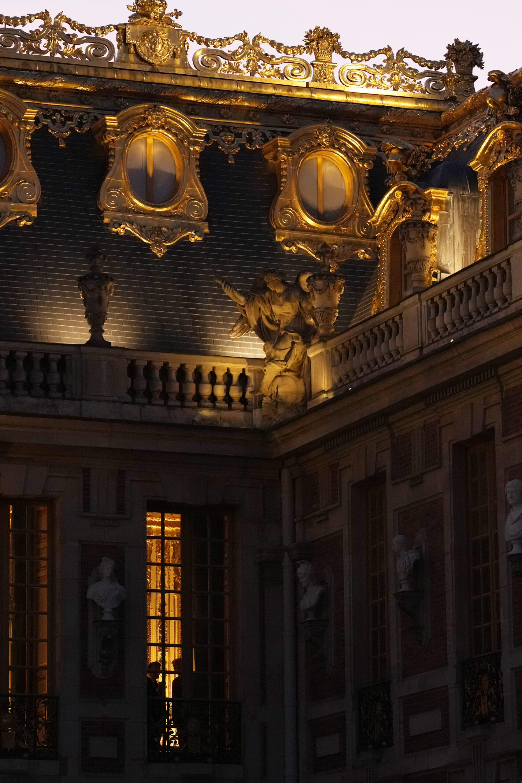 The roofs of the Marble Court at the Palace of Versailles at dusk, gilded leaf ornaments, sculpted attics, and illuminated attic statues for the dinner held on the sidelines of the Evian G7 summit.