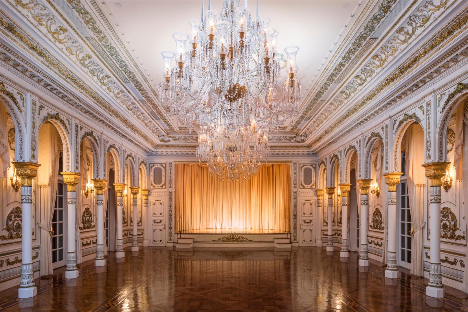One of Mar-a-Lago’s reception rooms: cascading crystal chandeliers, gilded columns and a stage with golden drapery.