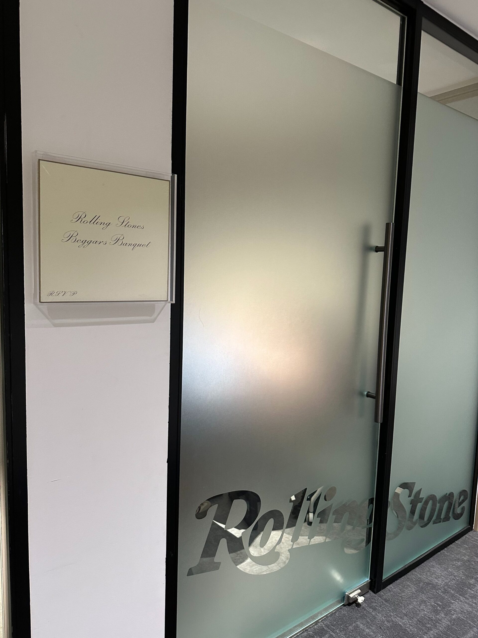 Salle Rolling Stones : under glass, the crème cover of Beggars Banquet (1968), on the frosted glass door, the band lettering. Photo : Crystal (@crystalsssup) / X.