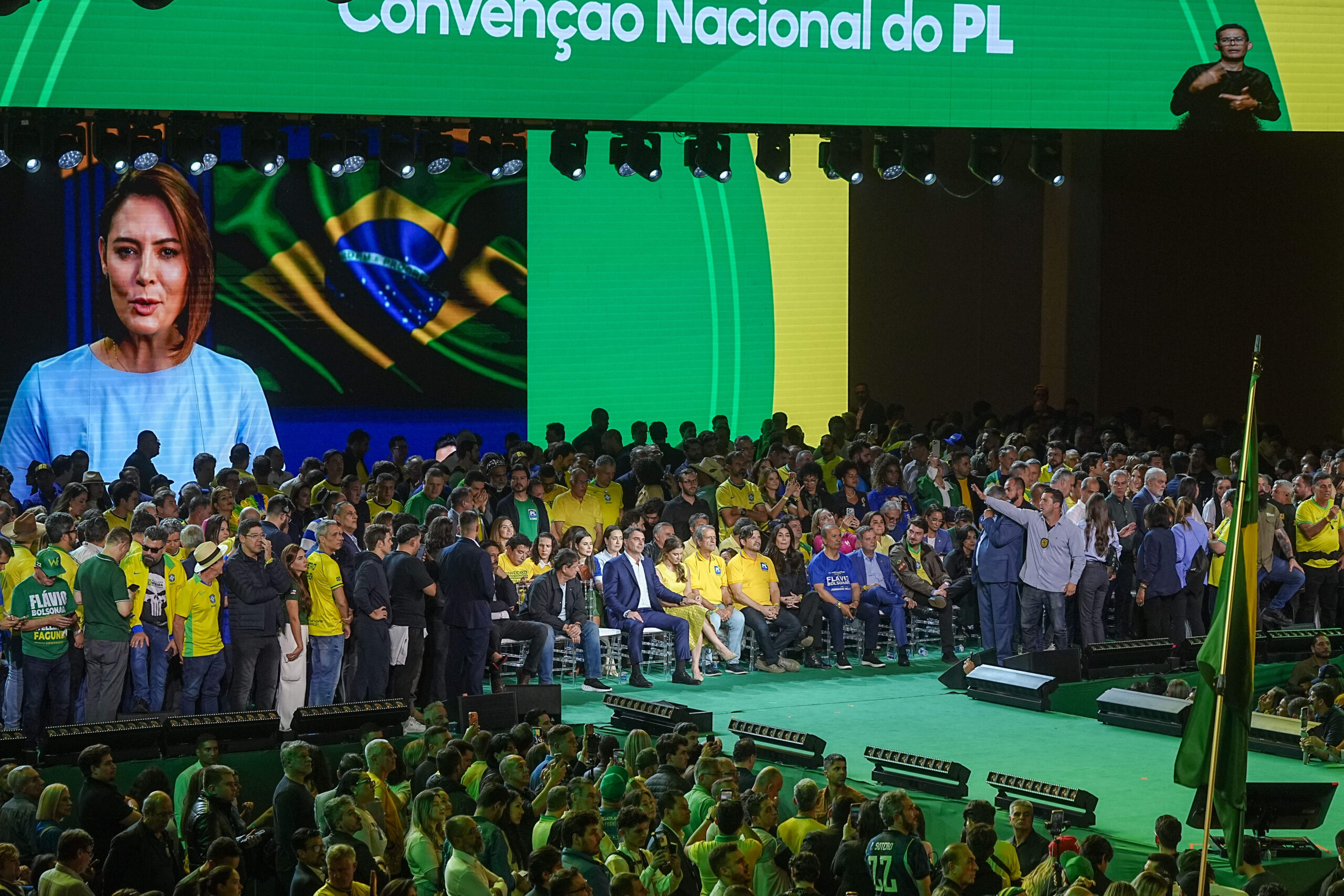 Michelle Bolsonaro s’adresse à la convention du PL par message vidéo. Figure du monde évangélique, l’ancienne première dame complète une mise en scène familiale faite d’absences : le père recréé par l’IA, l’épouse en visioconférence, et sur scène le fils investi.