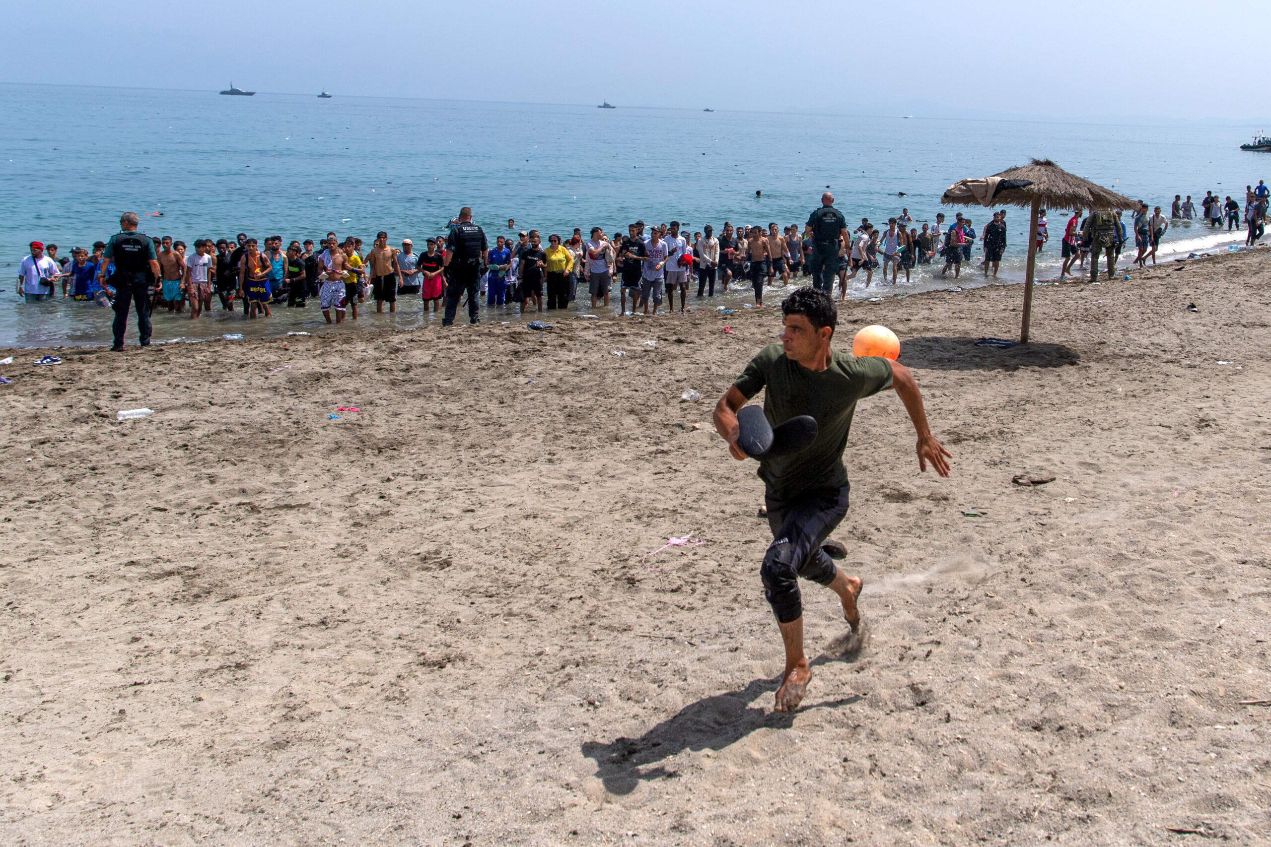 Sur la plage du Tarajal, un homme échappe au cordon policier qui boucle l'accès au rivage, vendredi 31 juillet — au troisième jour de la crise, la Guardia Civil regroupe désormais les arrivants au bord de l'eau. © AP Photo/Antonio Sempere/SIPA