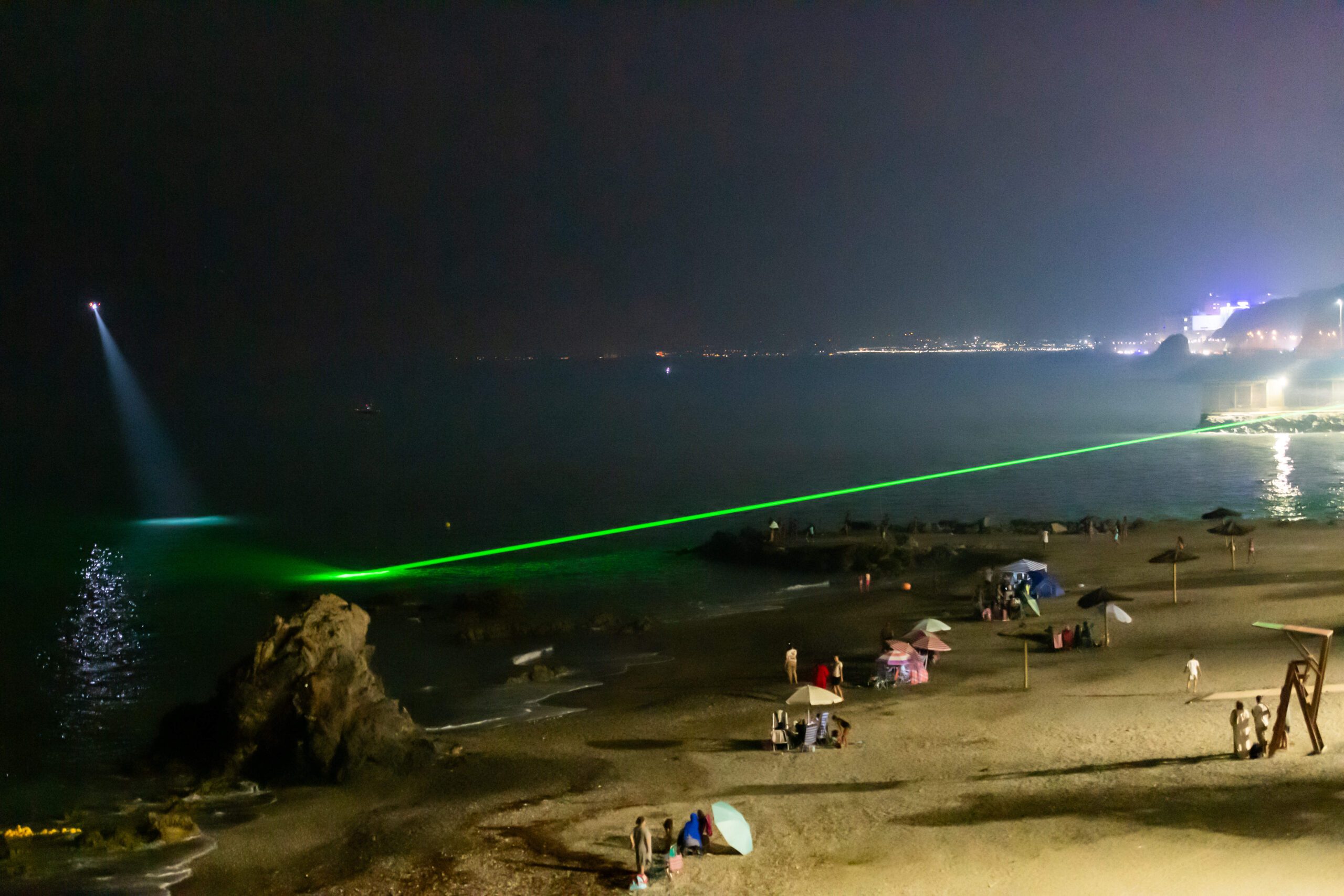 Dans la nuit du 29 juillet, le laser de la Guardia Civil balaie la baie pour repérer les nageurs qui tentent de rejoindre Ceuta, sous le projecteur d'un hélicoptère. © AP Photo/Antonio Sempere/SIPA
