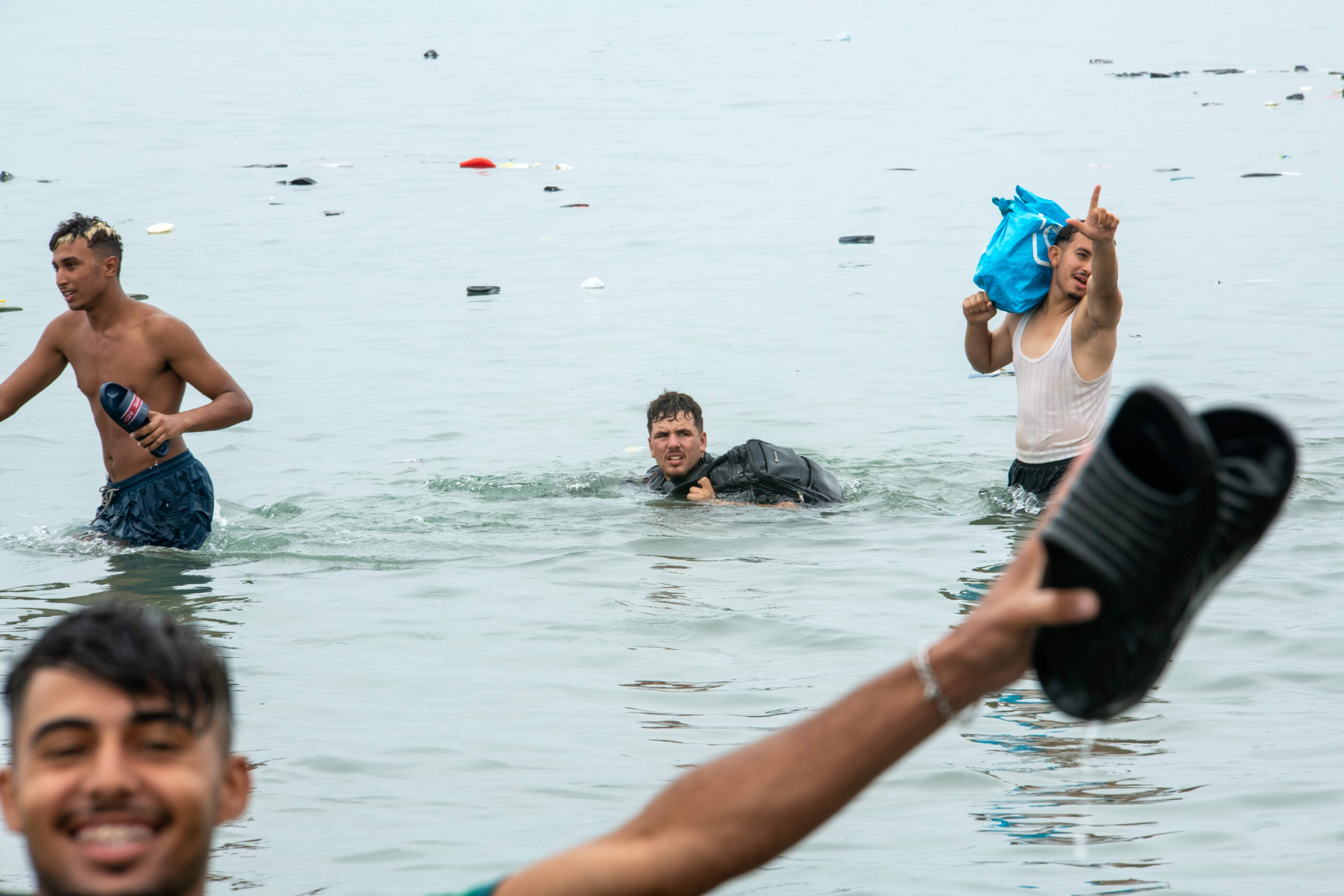 Un homme nage vers Ceuta, son sac à dos hors de l'eau, au milieu des affaires abandonnées qui dérivent dans le détroit, le 31 juillet 2026. Photo : Juan Carlos Lucas