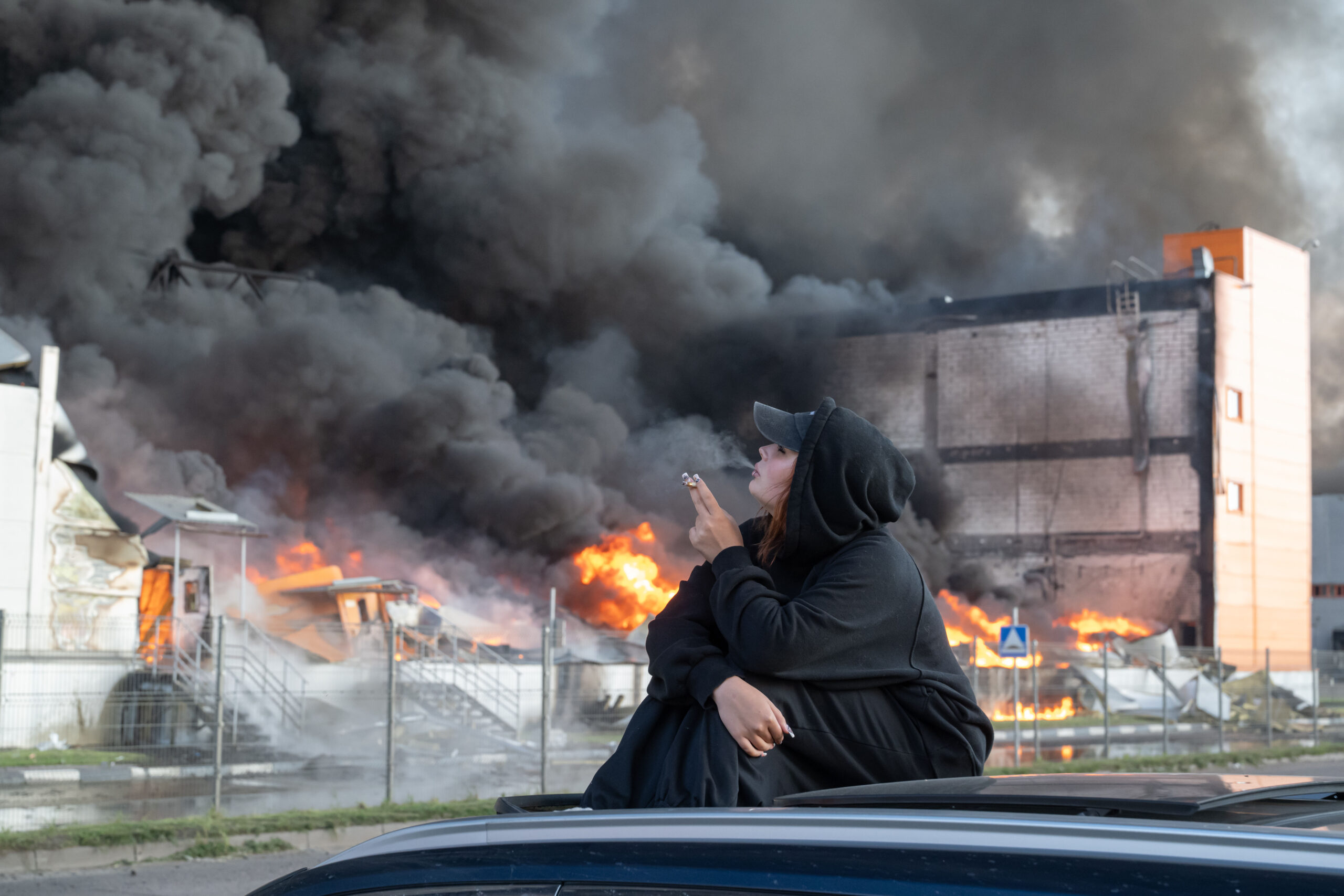 Une femme fume en observant un entrepôt en feu dans la zone d'Utkina Zavod, près du village de Novosaratovka. Photo: Stringer / SOPA Images/SIPA