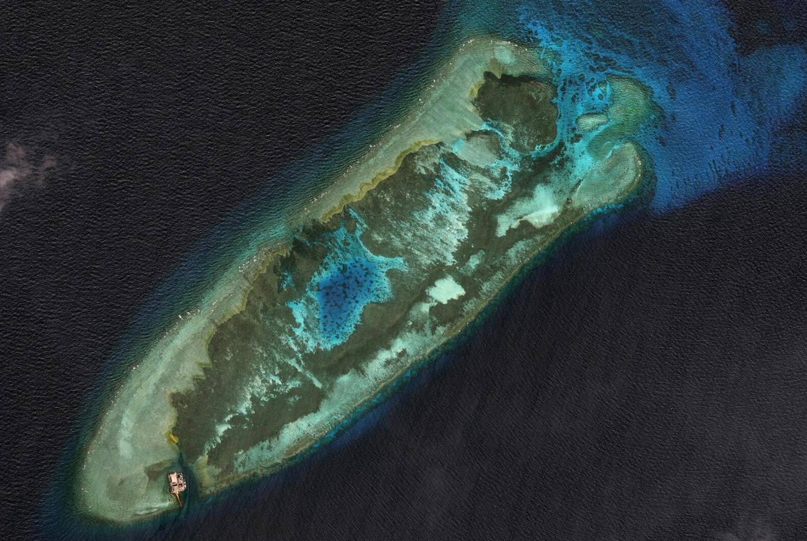 The Fiery Cross Reefs (Yongshu), in the Spratly archipelago, ahead of Beijing’s large-scale reclamation works in 2014. Barely emerging at high tide and occupied since 1988 by a simple observation post, this coral reef was still part of a sea that maps depicted as a “vast white and empty space,” a fluid domain of circulation that China now claims almost entirely under the ‘nine-dash line.’