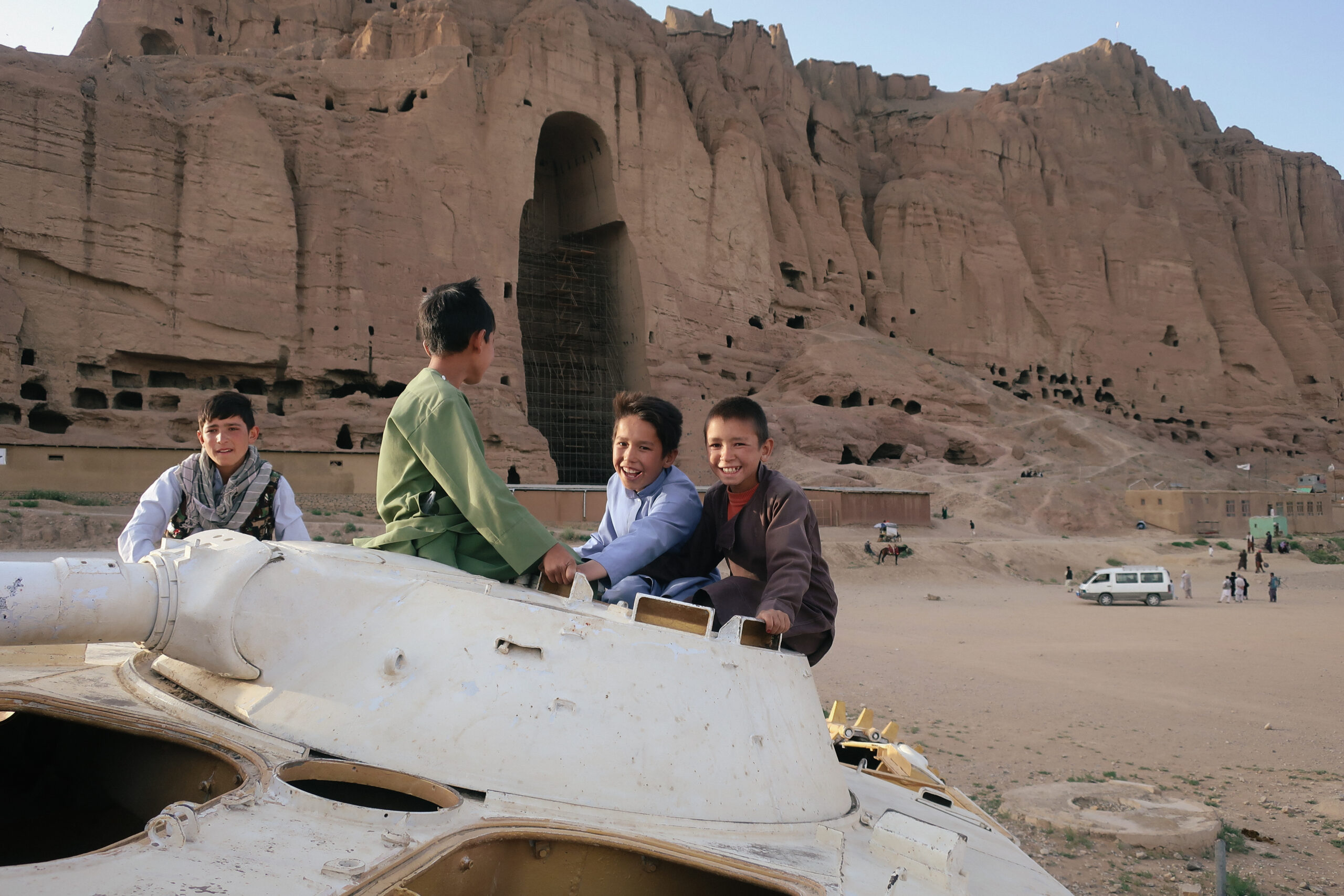 Des enfants sur la tourelle d'un char soviétique, face à la niche vide du grand Bouddha de Bamyan, mettent en scène la « pacification » talibane. © Nicolò Sancassiani.